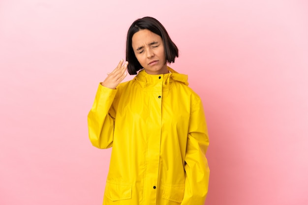 Young latin woman wearing a rainproof coat over isolated background with tired and sick expression