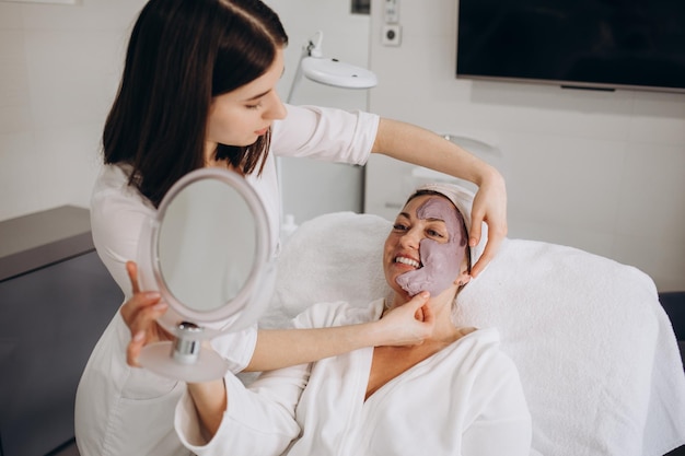 Young latin woman wearing towel looking face on mirror at beauty center