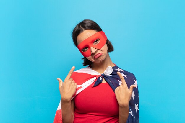 Young latin woman with a bad attitude looking proud and aggressive, pointing upwards or making fun sign with hands