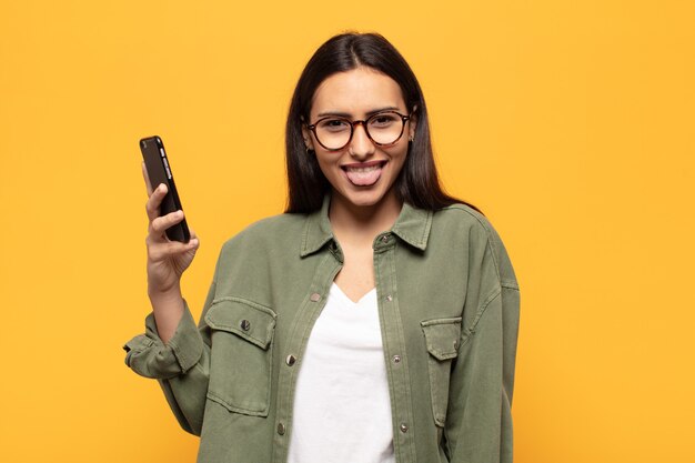 Young latin woman with cheerful, carefree, rebellious attitude, joking and sticking tongue out, having fun