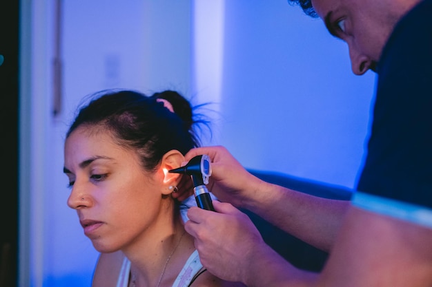 Photo young latin woman with ear problems being checked by a physician through an otoscope