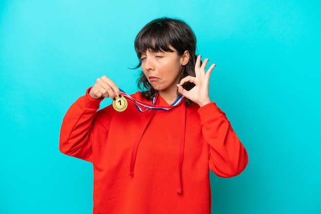 young latin woman with medals isolated on blue background