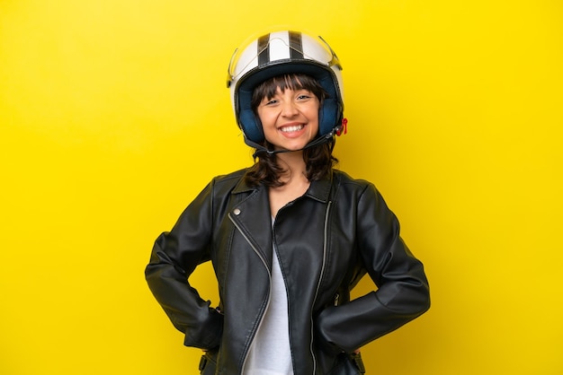 Young latin woman with a motorcycle helmet isolated on yellow background