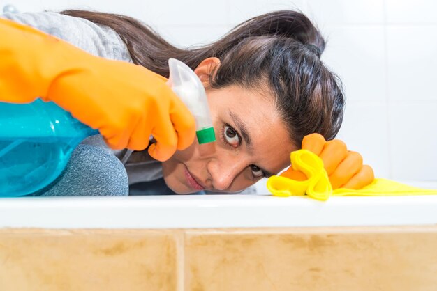 Young latina woman beautiful cleaning the bathroom wearing gloves