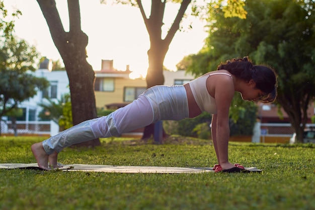 Young latina woman exercises with dumbbells in parkxA