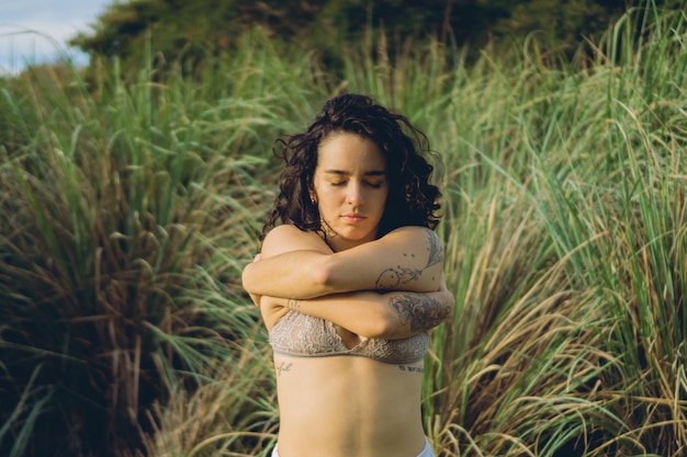 Young latina woman in lingerie in connection with nature embracing herself selflove