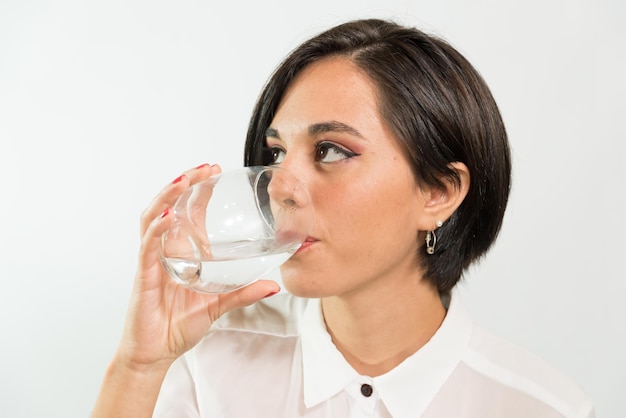 Young latina woman looking to the side drinking water dieting