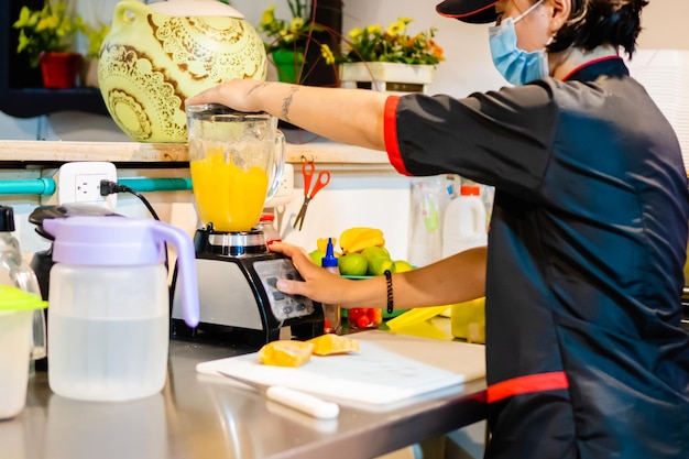 Young latina woman waitress making natural fruit juice mango local business