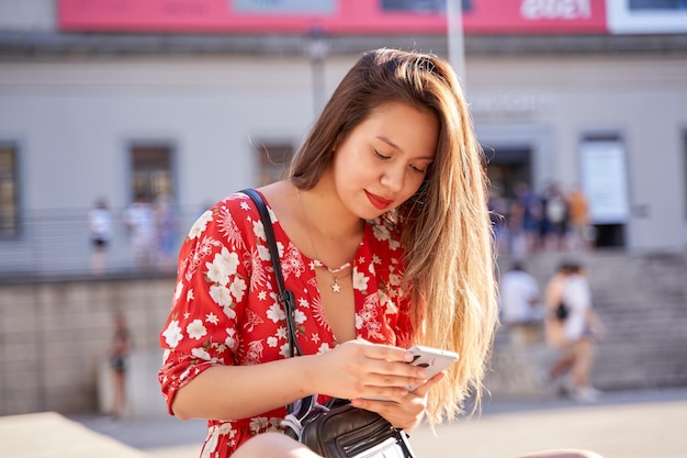 Young latina woman with long blonde hair using her smart phone\
for social networking