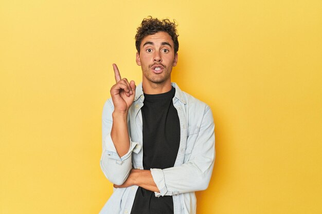 Young latino man posing on yellow background having some great idea concept of creativity