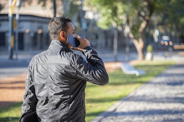 Young latino man talking on the mobile phone seen from behind with copy space