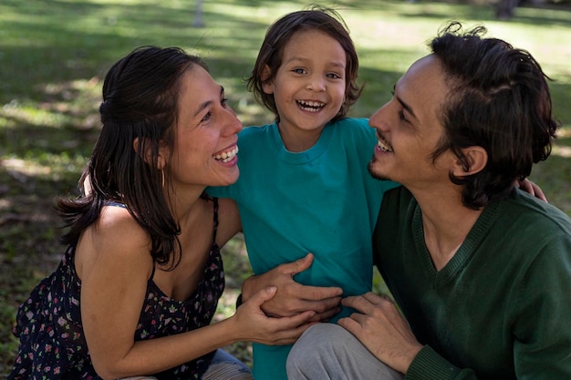 Young Latino parents happily share with their 3 year old son at the park Family concept