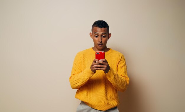 Young latinx man surprised using a mobile phone looking a message