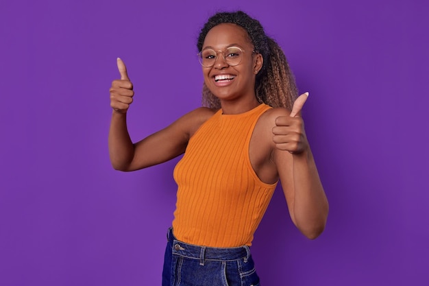 웃는 젊은 아프리카계 미국인 여성은 스튜디오에서 엄지손가락을 나타니다.