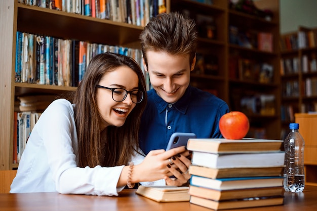 young laughing couple having fun by learning in the library after classes