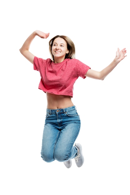 Young laughing jumping girl in a red tank top and jeans. Happy time. . Vertical.