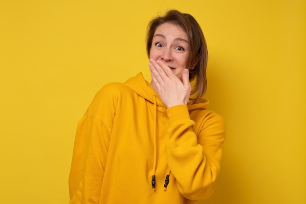 Young laughing woman covering her mouth being surprised with news. Studio shot