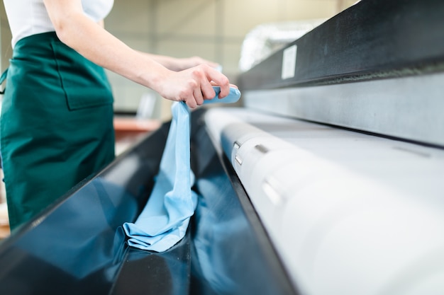 Young laundry worker pats the linen on the automatic machine at the dry cleaners.