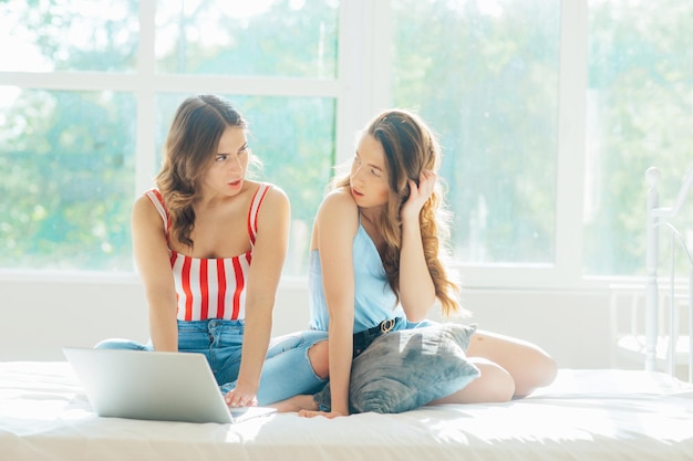 young lesbian couple with laptop on bed