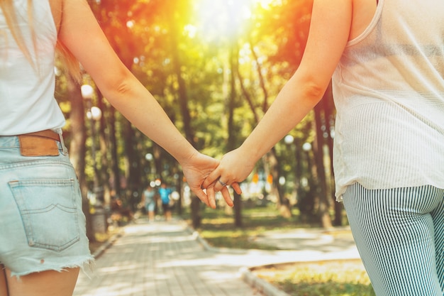 Young lesbian LGBT couple holding hands walking in the park