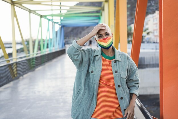 Young lesbian wearing LGBT rainbow flag pride mask - Focus on face