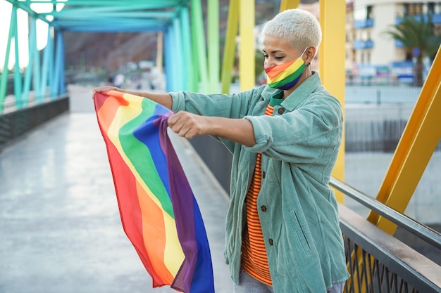 Young lesbian woman holding rainbow lgbt gay flag - Focus on face