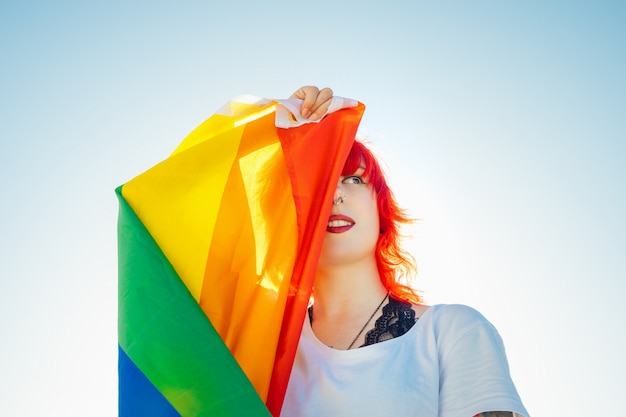 Young lesbian woman with the flag of pride covering her\
eye