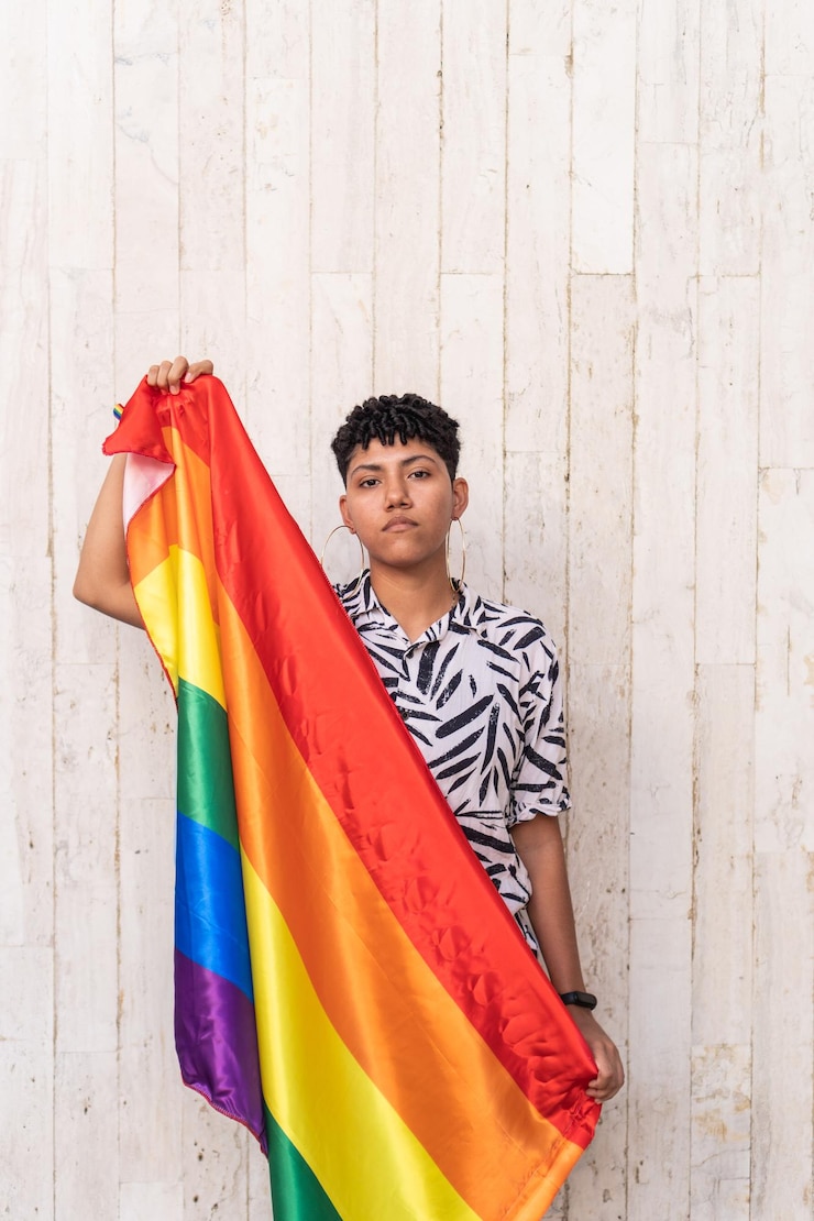 路上で虹色の旗でポーズをとる若いLGBTの女性