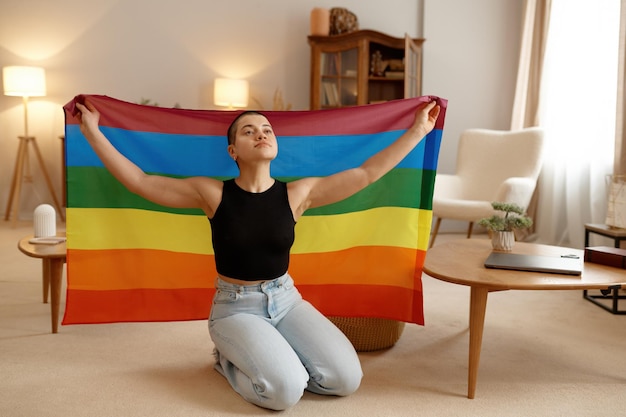 Young lgbt woman with rainbow flag in raised hands feeling proud of her sexual orientation selfacceptance concept