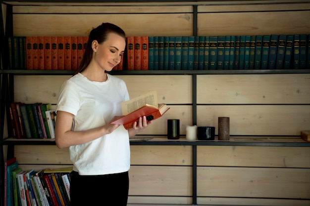 Young librarian searching books and taking one book from library bookshelf