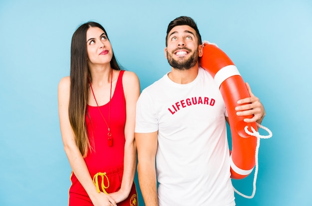 Young lifeguard couple isolated dreaming of achieving goals and purposes
