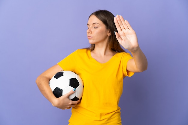 若いリトアニアのサッカー選手の女性が紫色の背景に分離し、停止ジェスチャーをして失望した