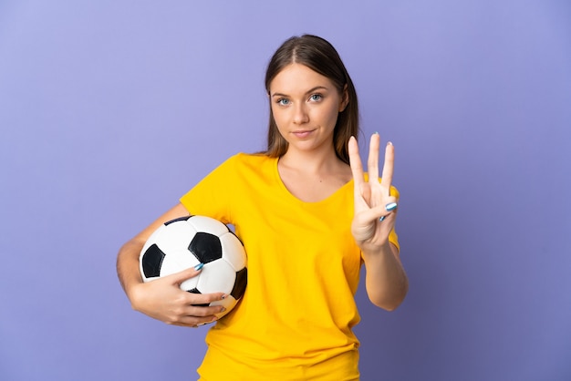 Young Lithuanian football player woman isolated on purple wall happy and counting three with fingers