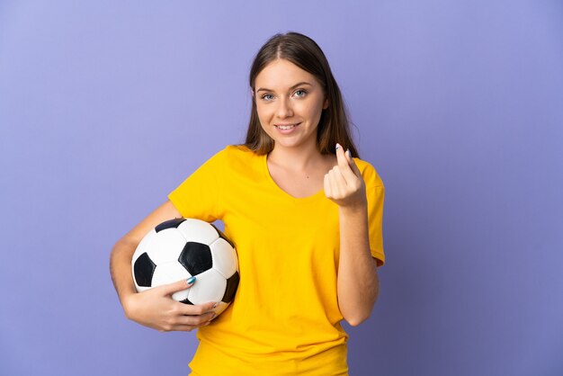 Young Lithuanian football player woman isolated on purple wall making money gesture