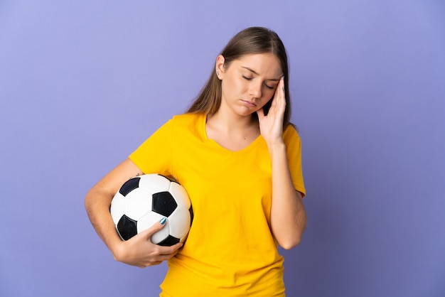 Young Lithuanian football player woman isolated on purple wall with headache