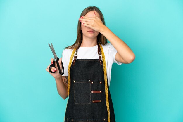 Young Lithuanian seamstress woman isolated on blue background covering eyes by hands. Do not want to see something