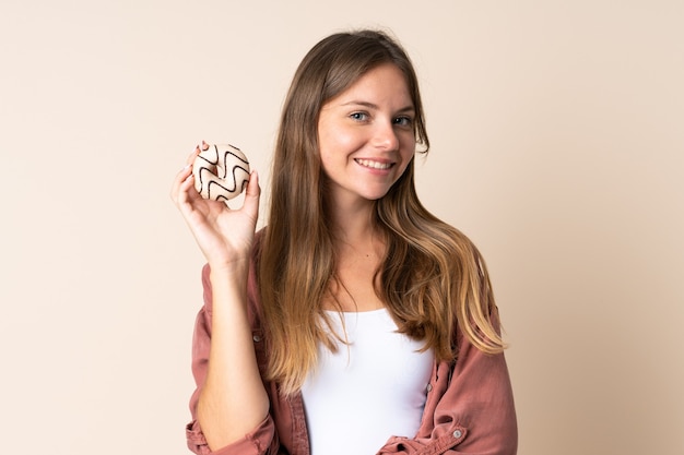 Young Lithuanian woman on beige holding a donut and happy