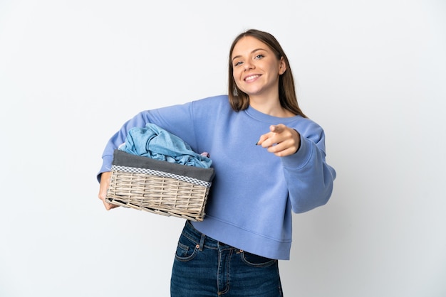 Young Lithuanian woman holding a clothes basket isolated on white wall pointing front with happy expression