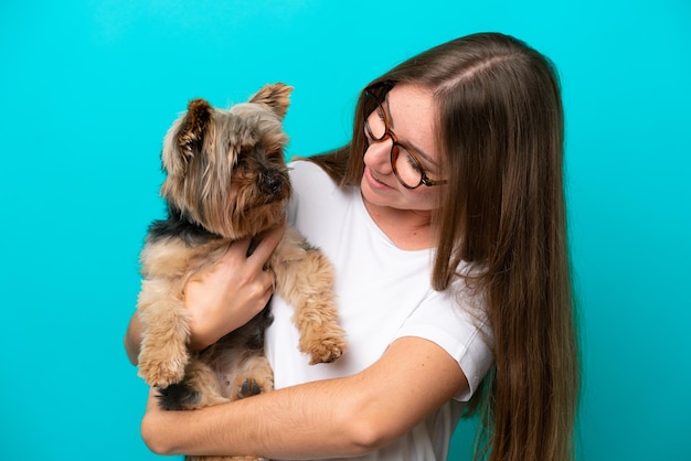 青い背景で隔離の犬を保持している若いリトアニアの女性