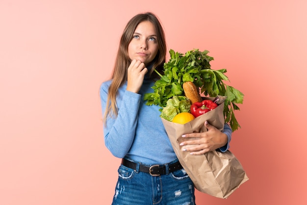 Young Lithuanian woman holding a grocery shopping bag and looking up