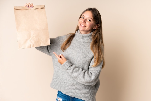 Young Lithuanian woman holding a grocery shopping bag and pointing it