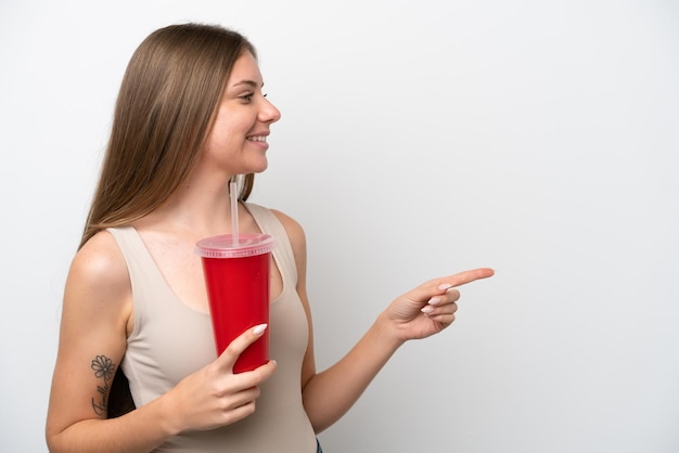 Молодая литовская женщина, держащая прохладительные напитки на белом фоне, указывая в сторону, чтобы представить продукт