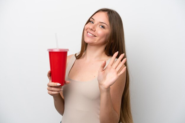 Young Lithuanian woman holding refreshment isolated on white background saluting with hand with happy expression