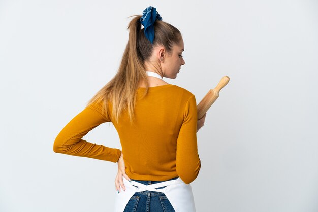 Foto giovane donna lituana tenendo un mattarello isolato su sfondo bianco in posizione posteriore e guardando il lato