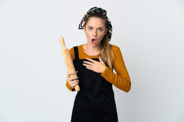 Young Lithuanian woman holding a rolling pin isolated on white background surprised and shocked while looking right