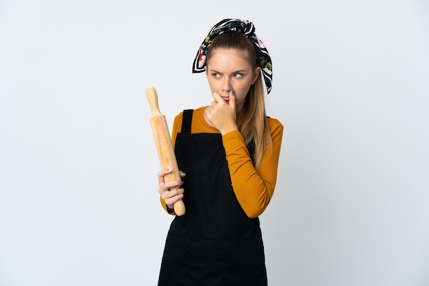 Young Lithuanian woman holding a rolling pin isolated on white background
