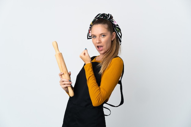 Young Lithuanian woman holding a rolling pin isolated on white wall celebrating a victory