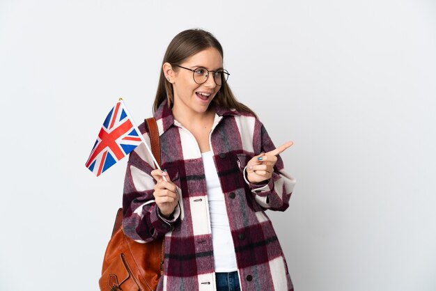 Young Lithuanian woman holding an United Kingdom flag isolated on white background pointing finger to the side and presenting a product