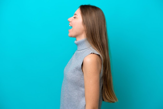 Young Lithuanian woman isolated on blue background laughing in lateral position