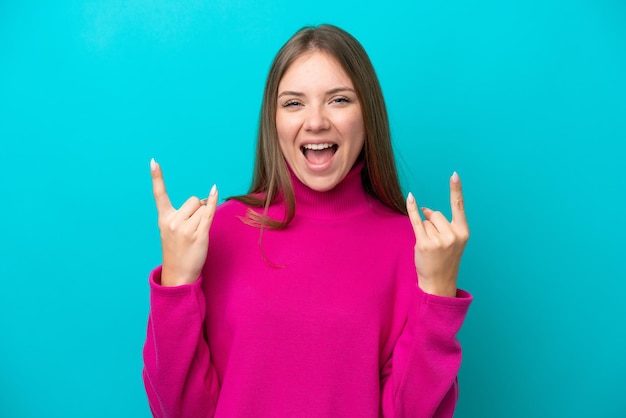 Young Lithuanian woman isolated on blue background making horn gesture